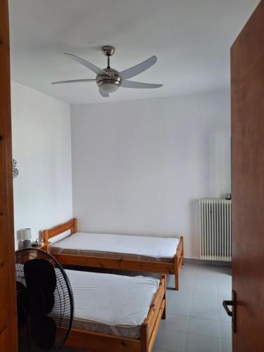 a room with two beds and a ceiling fan at Με θέα τον όρμο της Βάρης in Vari