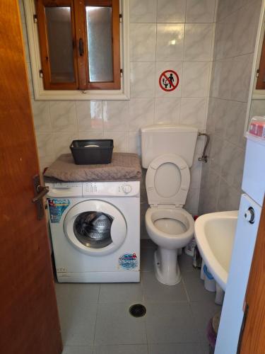 a small bathroom with a washing machine and a toilet at Με θέα τον όρμο της Βάρης in Vari