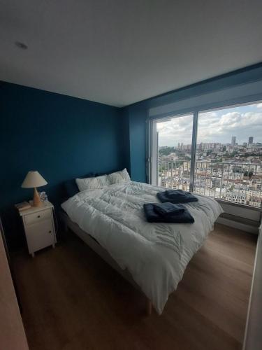 une chambre avec un grand lit et une grande fenêtre dans l'établissement Paris La Défense, balcon et vue d'exception 24e etage, à Puteaux