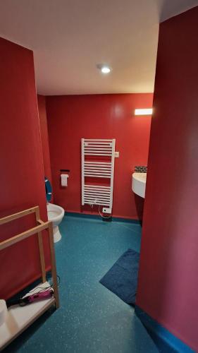La salle de bains rouge est pourvue de toilettes et d'un lavabo. dans l'établissement F3 original Maison bourgeoise Port Boinot, à Niort