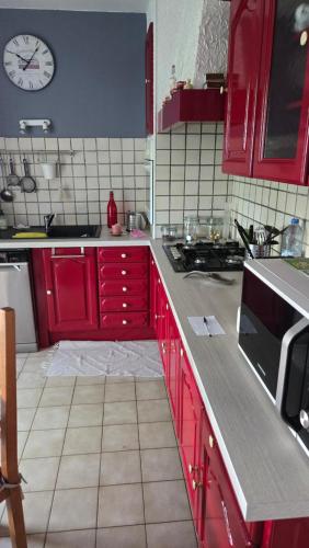 une cuisine avec des placards rouges et une horloge murale dans l'établissement Le Bleuet de Montbazon, à Montbazon