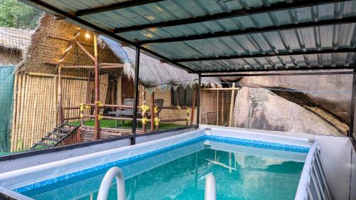 a house with a swimming pool and a bird cage at Chanaka Eco Camp ( Adventure Assam ) in Pakariāmukh