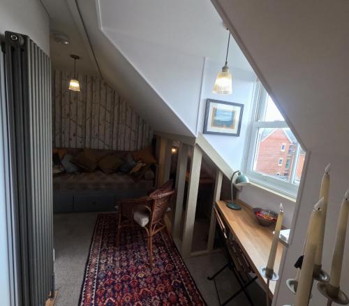 an attic room with a staircase with a couch and a table at St Elmo Felixstowe in Felixstowe