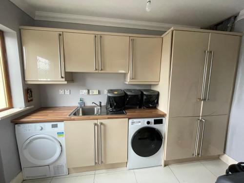 a small kitchen with a washing machine and a sink at Teach Mhaureen in Gortahork