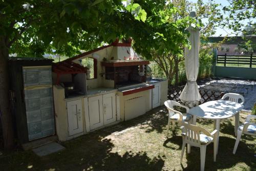 a barbecue grill in a backyard with a table and chairs at Dimitris house in Paralía Avdhíron
