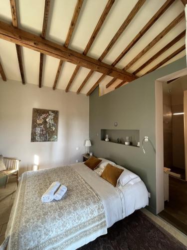 une chambre avec un grand lit dans une pièce avec des plafonds en bois dans l'établissement Domaine des Grillons, à Réauville