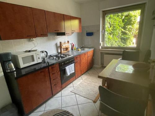 eine Küche mit Mikrowelle und Herd und einem Fenster in der Unterkunft MAD Ferienwohnungen 1 in Dortmund