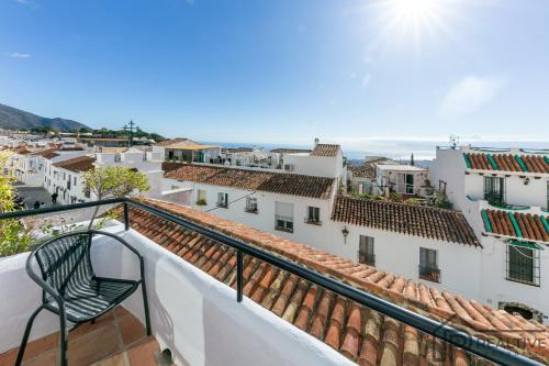 a chair on a balcony with a view of a city at La Casa de la Iglesia in Mijas
