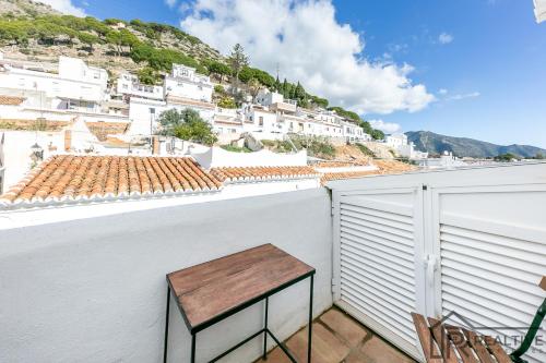 a wooden bench on a balcony with white buildings at La Casa de la Iglesia in Mijas