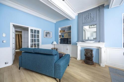 un salon bleu avec un canapé bleu et une cheminée dans l'établissement La Belle Epoque, à Bayeux