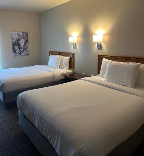 two beds in a hotel room with white sheets at The Sawmill Inn in Houston