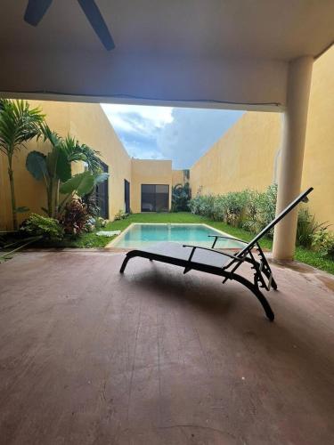 a hammock in front of a house with a swimming pool at casa de una planta con alberca in Mérida