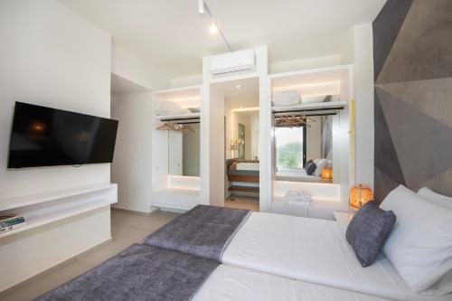 a bedroom with a white bed with a flat screen tv at Porti Villas Aphrodite in Asómatoi