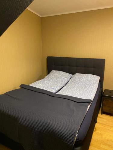a bed with a black headboard in a room at Leilighet med sydvendt balkong in Ålesund