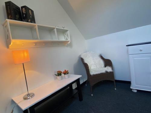a desk with a lamp and a chair in a room at Dejlig gårdhave 5 soveværelser in Harboør