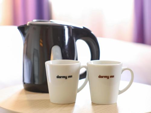a coffee pot and two coffee cups on a table at Dormy Inn Sapporo Annex in Sapporo