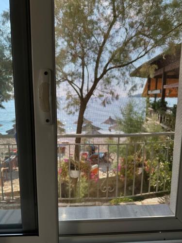 a window with a view of a patio with a tree at Potami Seashell in Himare