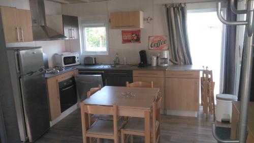 La cuisine est équipée d'une table, d'un réfrigérateur et d'un évier. dans l'établissement Story familiale, à Lit-et-Mixe