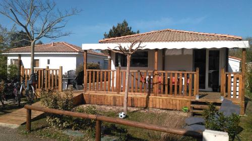 une maison avec une terrasse couverte en bois et une clôture dans l'établissement Story familiale, à Lit-et-Mixe