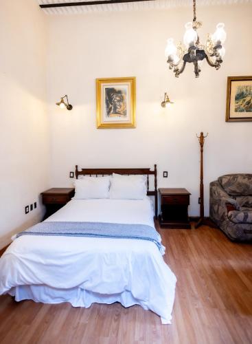 a bedroom with a bed and a couch and a chandelier at Hacienda Gobernadores in Mexico City