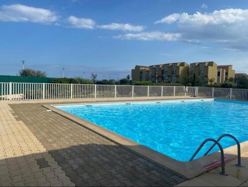 une grande piscine bleue devant un immeuble dans l'établissement T2 Leucate climatisé - Vue mer, piscine et plage, à Leucate-Plage