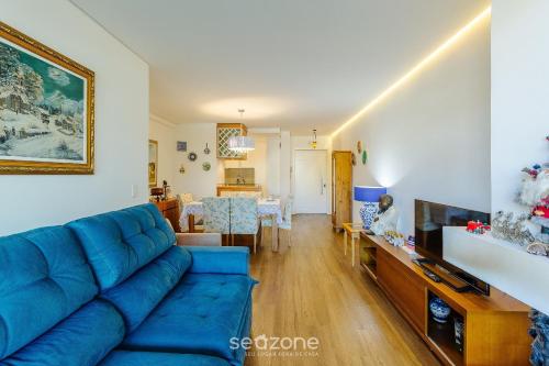 ein Wohnzimmer mit einem blauen Sofa und einem Esszimmer in der Unterkunft Apto em Canela de frente ao lago dos patos CBL307 in Canela