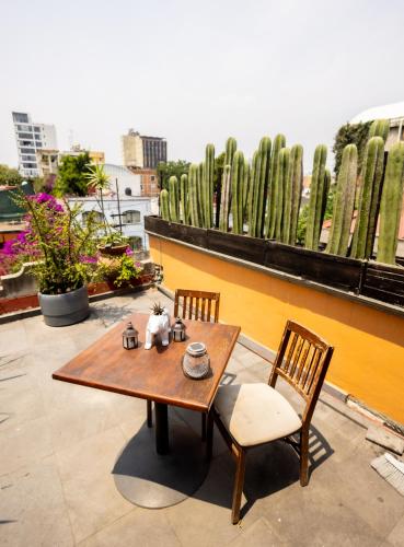 a wooden table and chairs on a balcony with cactus at Hacienda Gobernadores in Mexico City