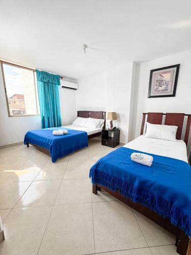 two beds in a room with blue sheets at Hotel Puerto Bahia in San Gil