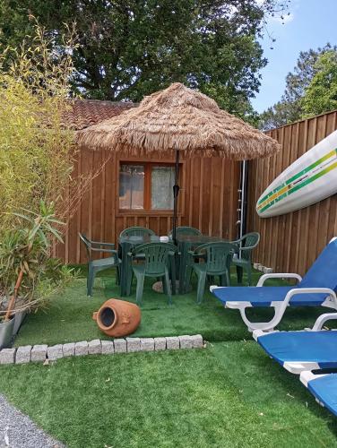 une arrière-cour avec une table, des chaises et une planche de surf dans l'établissement Au rocher de Pascal lit mezzanine, à Montalivet-les-Bains