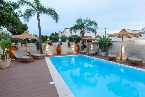 a swimming pool with chairs and umbrellas on a patio at Dimora Nesea in Cozze
