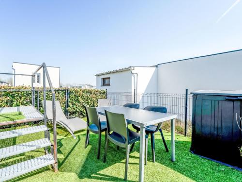 eine Terrasse mit einem Tisch und Stühlen auf dem Rasen in der Unterkunft Holiday Home New Dahlia 1 by Interhome in Bredene