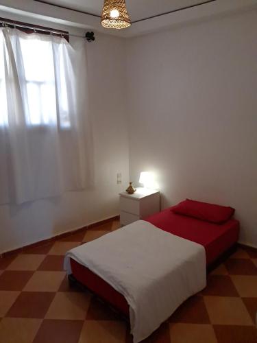 a bedroom with a red bed and a window at Buena vista morroco GUEST HOUSE in Tamraght Ouzdar