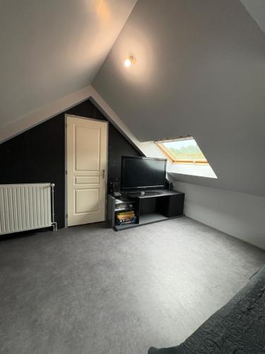 une chambre mansardée avec une télévision et une porte dans l'établissement Doryan, à Sargé-lès-Le Mans