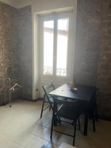 a dining room with a table and chairs and a window at Charmant 2 pièces village historique la turbie in La Turbie