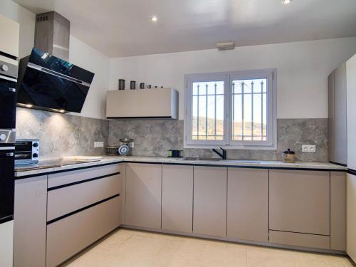 une grande cuisine avec des armoires blanches et une fenêtre dans l'établissement Holiday Home Villa Mehdaeve by Interhome, au Luc