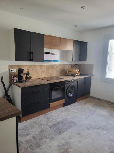 - une cuisine avec des armoires noires et un lave-vaisselle dans l'établissement T2 jardin neuf, à Béziers