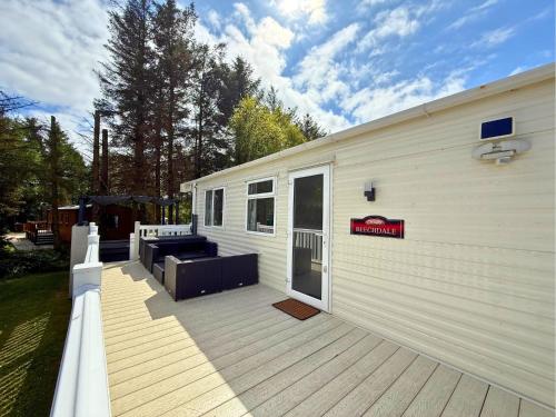a large deck with a couch on the side of a house at Private Hot Tub & Spacious Decking Area in Northumberland, Dog-Friendly, Free Golf Access in Swarland