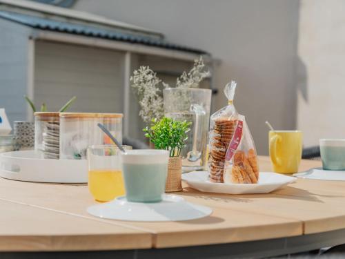 - une table en bois avec des assiettes de nourriture et de boissons dans l'établissement Holiday Home La Colombe by Interhome, à Saint-Lunaire