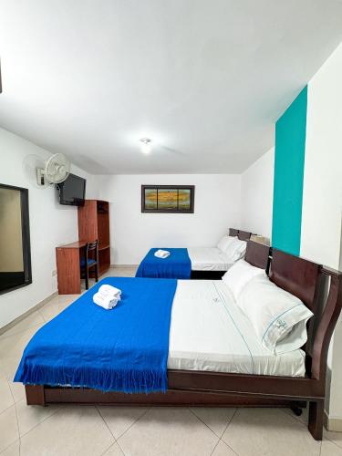 a bedroom with two beds and a flat screen tv at Hotel Puerto Bahia in San Gil