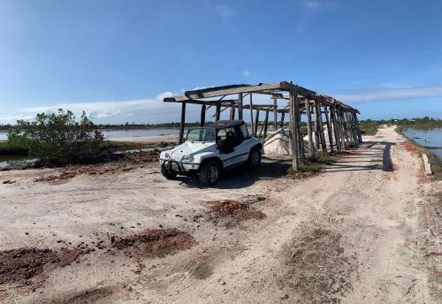 a small white car parked under a shed on a dirt road at Faith Home 2 in Arraial do Cabo