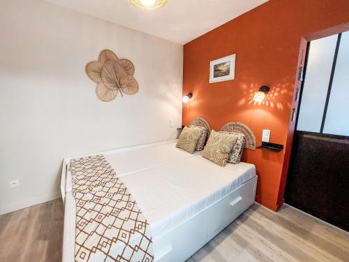 une chambre avec un lit avec un mur orange dans l'établissement Apartment Charme du Pouliguen by Interhome, au Pouliguen
