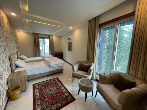 a bedroom with a bed and a couch and chairs at Sangha Cottage in Abbottābād
