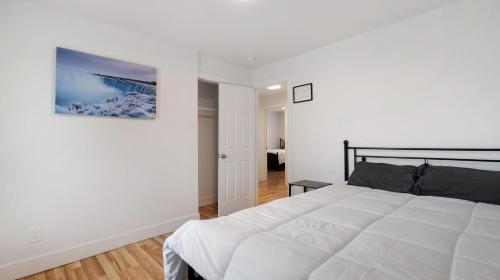 a bedroom with a white bed and a painting on the wall at Beautiful 4 bedroom home short walk to Niagara Falls in Niagara Falls