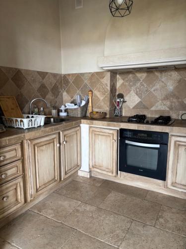 une cuisine avec des armoires en bois et un four à plaques de cuisson dans l'établissement Cassis vue mer, à La Celle-sous-Gouzon