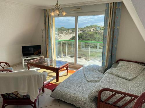 a living room with a bed and a large window at Escapade Sarah, appartement duplex in Fort-Mahon-Plage