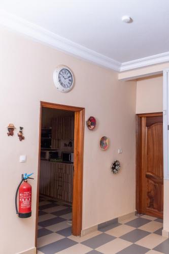 a room with a clock on the wall and a fire extinguisher at Résidence Koto in Dakar