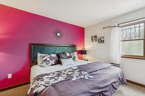 a bedroom with a pink wall and a bed at Grand Tomahawk Lodge in Tomahawk