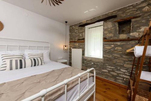 a bedroom with a bed and a stone wall at Toutounis House Kazaviti in Mikros Prinos