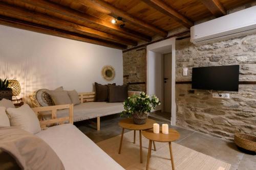 a living room with a couch and a tv on a stone wall at Toutounis House Kazaviti in Mikros Prinos