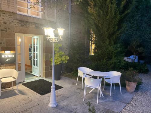 a table and chairs and a street light in a courtyard at Hôtel Victor Hugo in Pontorson